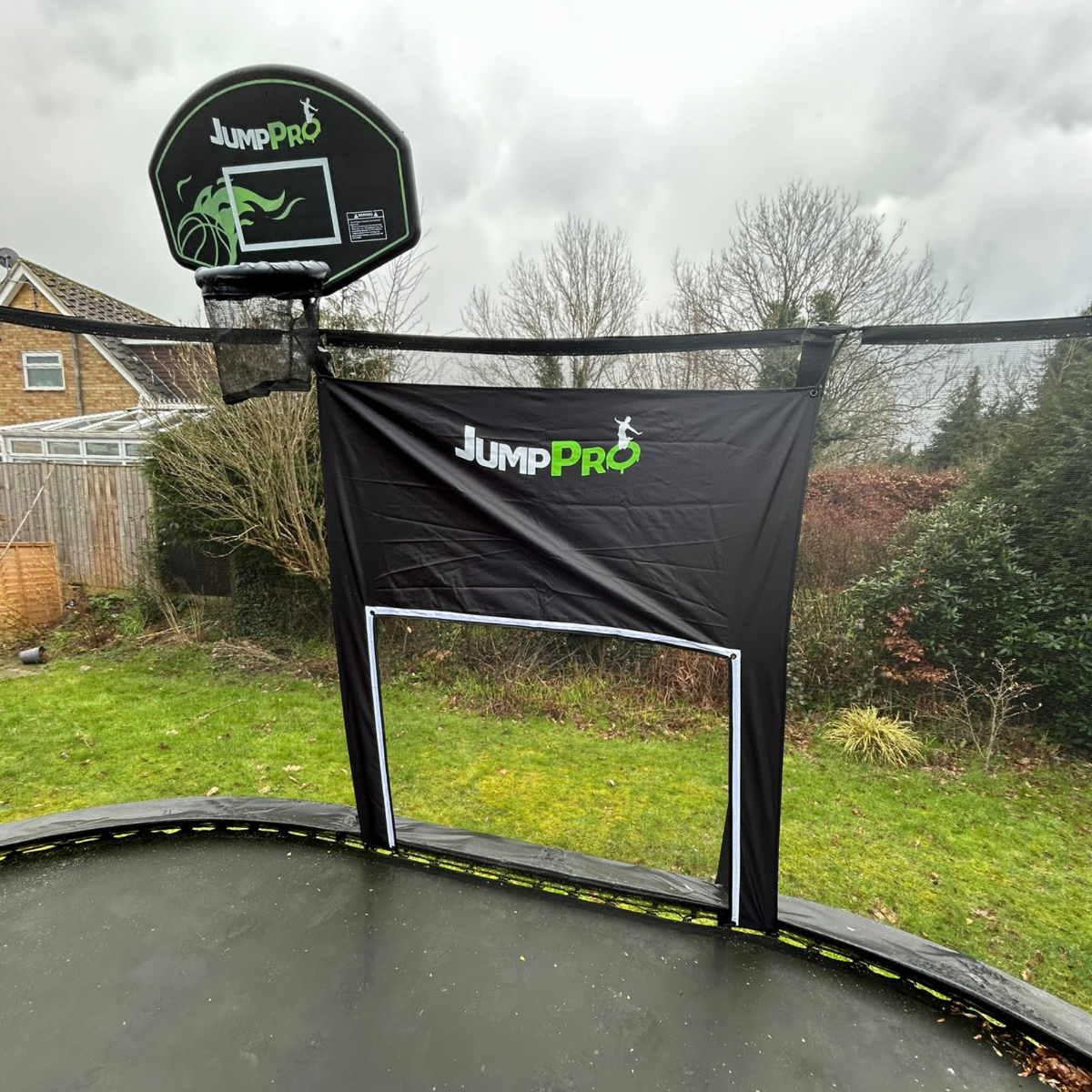 Trampoline with basketball hoop and safety net in a backyard setting
